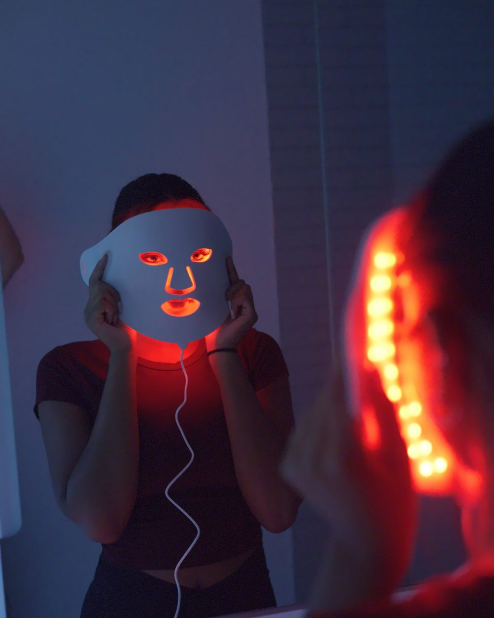 Woman at a mirror wearing an AWA LED face mask